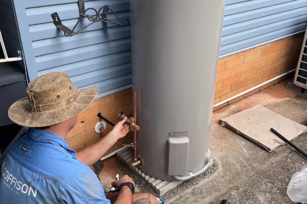Coffison Plumbing technician installing a hot water system outside a Brisbane home