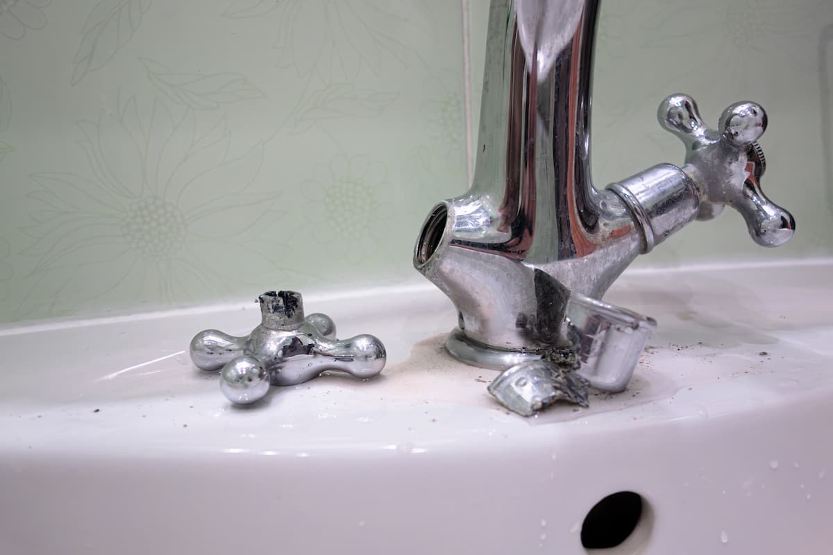 Broken tap handle on bathroom sink with loose parts scattered on basin.