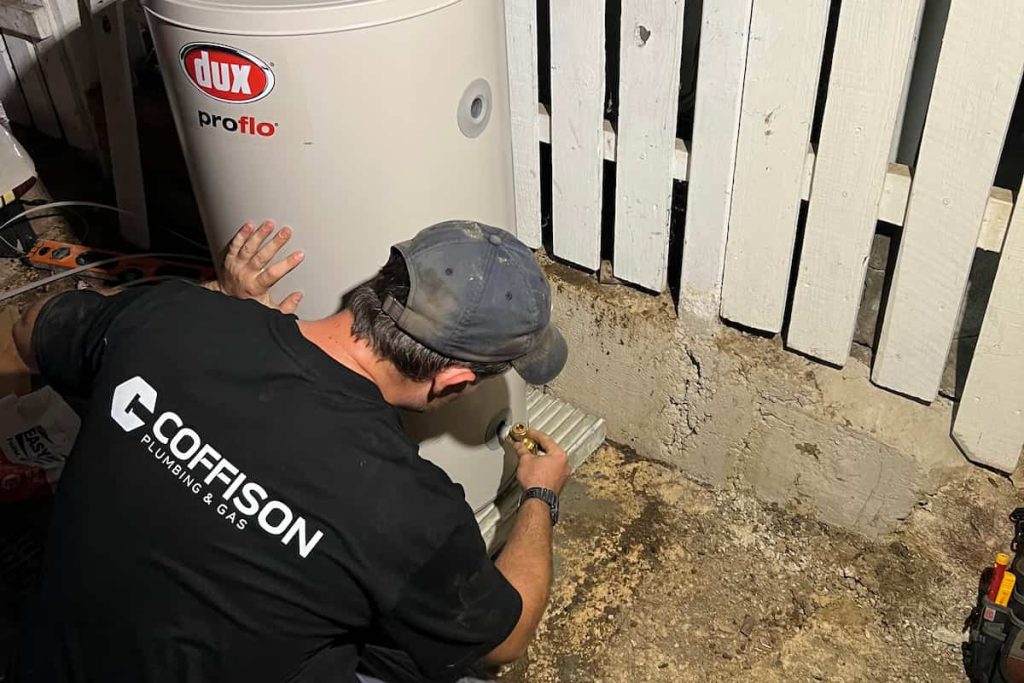 Coffison Plumbing technician installing a new Dux hot water system at a residential property in Brisbane.